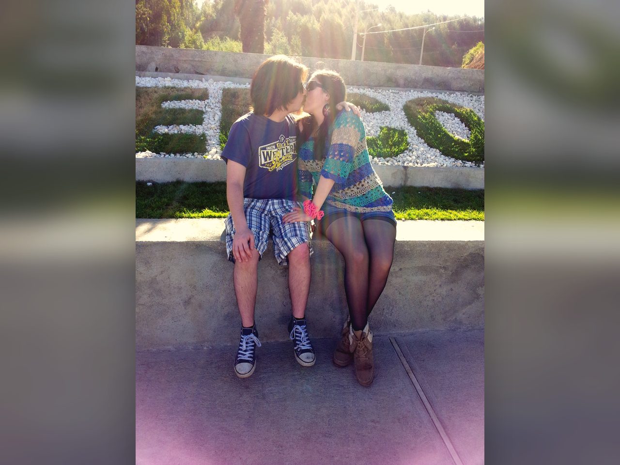 Pareja compartiendo un beso bajo la luz del sol.